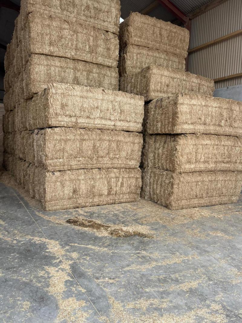 Stacks of hay bales inside a barn.