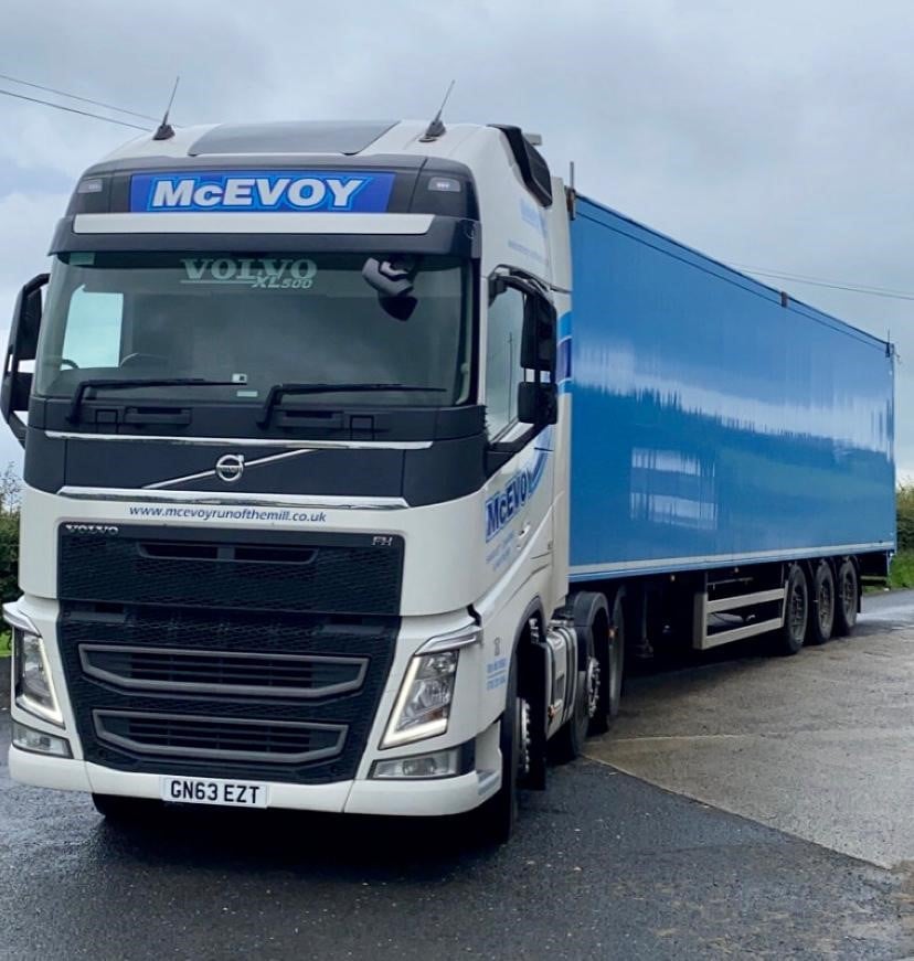 White truck with blue trailer labeled 'McEvoy' on a road.